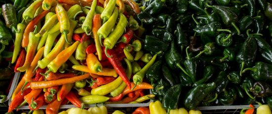 Vibrant peppers on display at a bustling Raleigh farmer's market, showcasing local produce.